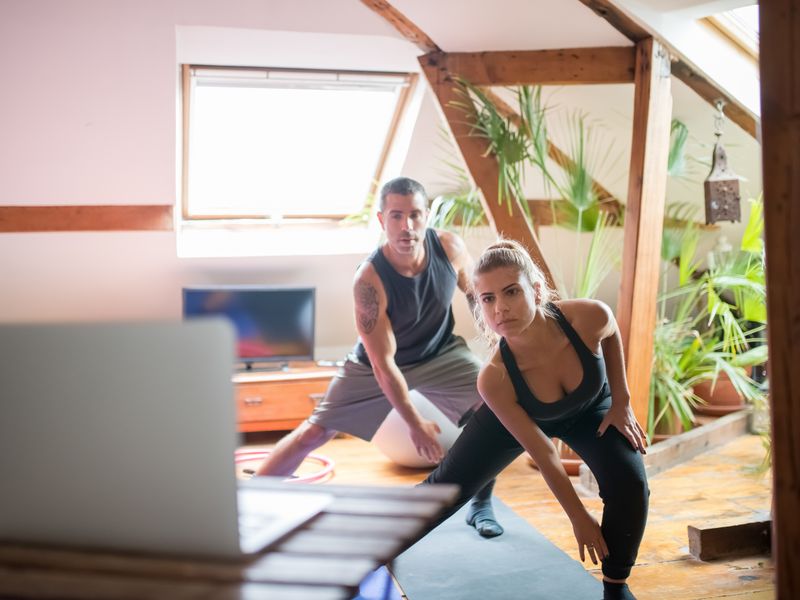 Two people following a guided online workout on a laptop at home
